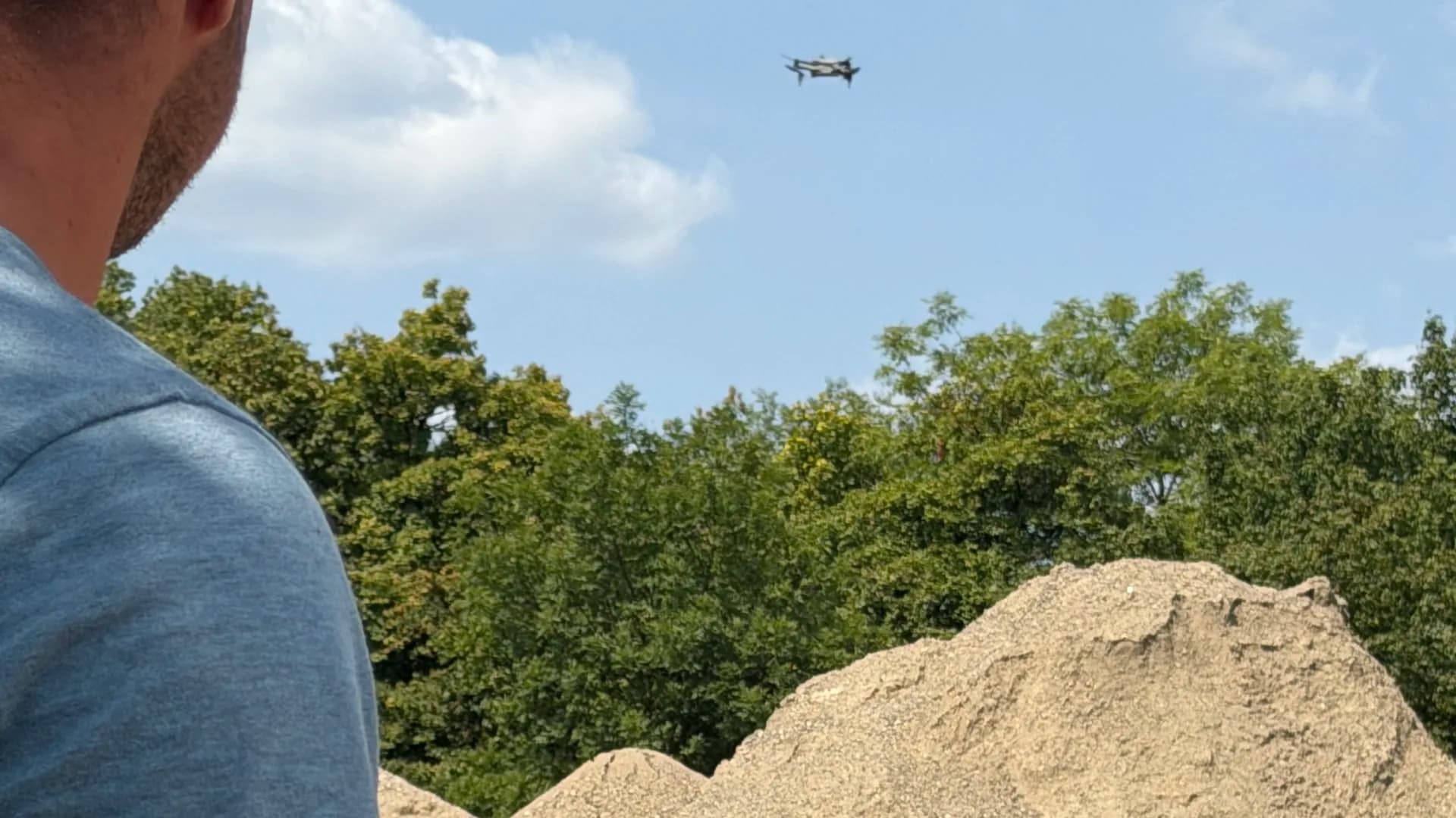 Drohnenpilot eines Straßenbaubetriebs fliegt ein Schüttgut-Haufwerk für die Volumenberechnung ab